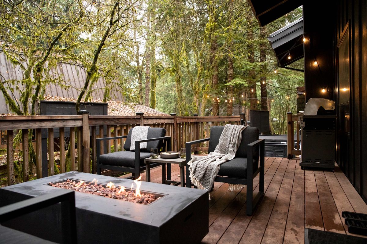 Back deck with lounge chairs and fire table in the trees
